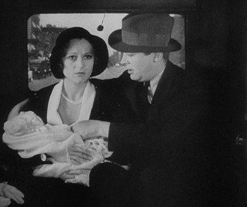 Movie still from “Bad Girl” (1931), directed by Frank Borzage – A man and a woman sitting in a car holding food; Medium shot, High angle