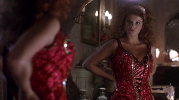 Movie still from “Blaze” (1989), directed by Ron Shelton – A woman in a red sequined dress looking at herself in the mirror; Medium shot, Low angle