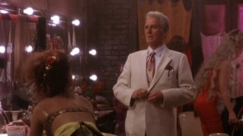 Movie still from “Blaze” (1989), directed by Ron Shelton – A man in a white suit standing in front of a mirror; Medium shot, Over the shoulder angle