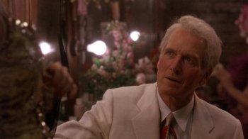 Movie still from “Blaze” (1989), directed by Ron Shelton – An older man wearing a white suit and red tie; Close Up shot, Over the shoulder angle