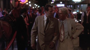 Movie still from “Blaze” (1989), directed by Ron Shelton – A couple of men standing next to each other on the street; Medium shot, Low angle