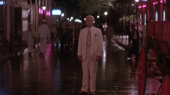 Movie still from “Blaze” (1989), directed by Ron Shelton – An older man in a white suit standing in the street; Wide shot, Low angle