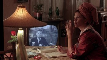 Movie still from “Blaze” (1989), directed by Ron Shelton – A woman sitting in front of a television; Medium shot, Over the shoulder angle
