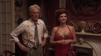 Movie still from “Blaze” (1989), directed by Ron Shelton – A man standing next to a woman in a red dress; Medium shot, Low angle