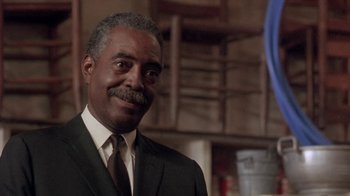 Movie still from “Blaze” (1989), directed by Ron Shelton – An older man wearing a suit and tie smiling; Close Up shot, Low angle