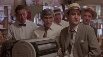 Movie still from “Blaze” (1989), directed by Ron Shelton – A group of men standing next to each other in a room; Medium shot, Low angle