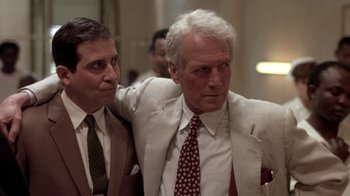 Movie still from “Blaze” (1989), directed by Ron Shelton – Two men in suits are standing next to each other; Medium shot, Low angle