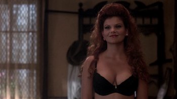 Movie still from “Blaze” (1989), directed by Ron Shelton – A woman in a black bra is posing for a picture; Close Up shot, Over the shoulder angle