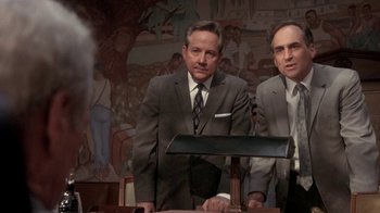 Movie still from “Blaze” (1989), directed by Ron Shelton – Two men in suits standing at a table; Medium shot, Low angle