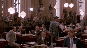 Movie still from “Blaze” (1989), directed by Ron Shelton – A group of men sitting in a room; Wide shot, High angle