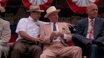 Movie still from “Blaze” (1989), directed by Ron Shelton – A couple of men sitting next to each other on a bench; Medium shot, Low angle
