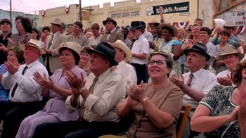 Movie still from “Blaze” (1989), directed by Ron Shelton – A group of people sitting in a crowd clapping; Medium shot, High angle