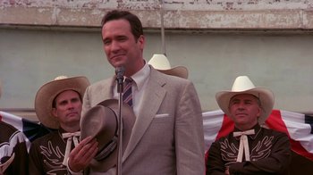 Movie still from “Blaze” (1989), directed by Ron Shelton – A man in a gray suit and a hat; Medium shot, Low angle