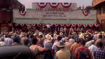 Movie still from “Blaze” (1989), directed by Ron Shelton – A crowd of people wearing cowboy hats in front of a building; Extreme Wide shot, High angle