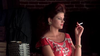 Movie still from “Blaze” (1989), directed by Ron Shelton – A woman in a red and white dress smoking a cigarette; Medium shot, Low angle