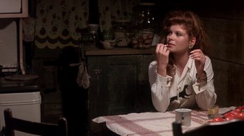 Movie still from “Blaze” (1989), directed by Ron Shelton – A woman sitting at a table in front of a cup of coffee; Medium shot, Over the shoulder angle