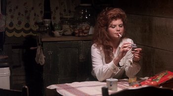 Movie still from “Blaze” (1989), directed by Ron Shelton – A woman sitting at a table with a cigarette in her mouth; Medium shot, Over the shoulder angle