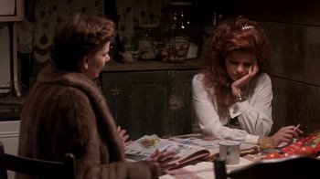 Movie still from “Blaze” (1989), directed by Ron Shelton – Two women sitting at a dinner table talking to each other; Medium shot, Over the shoulder angle