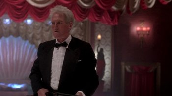 Movie still from “Blaze” (1989), directed by Ron Shelton – A man in a tuxedo holding a gun in his hand; Medium shot, Low angle