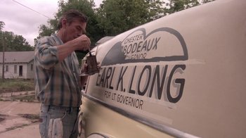 Movie still from “Blaze” (1989), directed by Ron Shelton – A man is painting the side of a car; Medium shot, Low angle