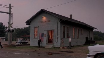 Movie still from “Blaze” (1989), directed by Ron Shelton – Two men standing outside of a building on the side of the street; Extreme Wide shot, High angle
