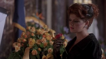 Movie still from “Blaze” (1989), directed by Ron Shelton – A woman holding a rose in front of a bouquet of flowers; Close Up shot, Over the shoulder angle