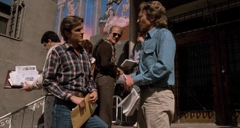 Movie still from “Body Double” (1984), directed by Brian De Palma – A group of men standing next to each other on the sidewalk; Wide shot, Low angle