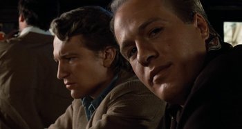 Movie still from “Body Double” (1984), directed by Brian De Palma – A couple of men sitting next to each other; Close Up shot, Low angle