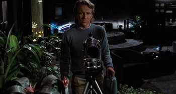 Movie still from “Body Double” (1984), directed by Brian De Palma – A man standing in front of a camera; Medium shot, Low angle