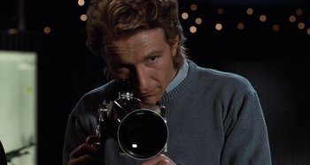 Movie still from “Body Double” (1984), directed by Brian De Palma – A man taking a picture with a camera; Close Up shot, Low angle