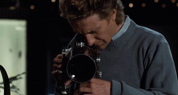 Movie still from “Body Double” (1984), directed by Brian De Palma – A man holding a camera up to his face; Close Up shot, High angle