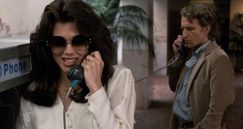 Movie still from “Body Double” (1984), directed by Brian De Palma – A woman talking on a phone next to a man; Close Up shot, Low angle
