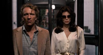 Movie still from “Body Double” (1984), directed by Brian De Palma – A man and a woman standing next to each other in front of a building; Close Up shot, Low angle