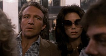 Movie still from “Body Double” (1984), directed by Brian De Palma – A man and a woman wearing sunglasses standing next to each other; Close Up shot, Low angle