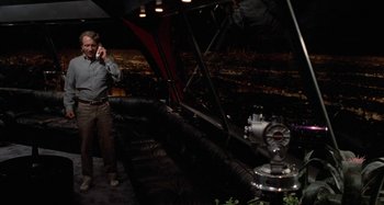 Movie still from “Body Double” (1984), directed by Brian De Palma – A man talking on a phone next to a fire hydrant; Wide shot, High angle