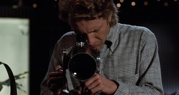Movie still from “Body Double” (1984), directed by Brian De Palma – A man holding a camera up to his face; Close Up shot, High angle