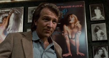 Movie still from “Body Double” (1984), directed by Brian De Palma – A man standing in front of a movie poster; Close Up shot, Low angle