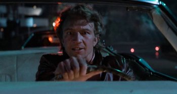Movie still from “Body Double” (1984), directed by Brian De Palma – A man driving a car at night in the dark; Close Up shot, Low angle