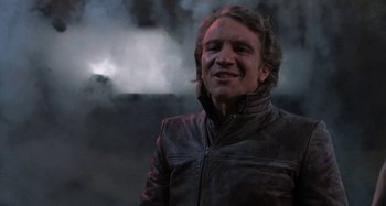 Movie still from “Body Double” (1984), directed by Brian De Palma – A man wearing a leather jacket standing in front of smoke; Close Up shot, Low angle