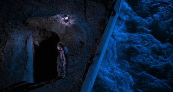 Movie still from “Body Double” (1984), directed by Brian De Palma – A man standing next to a body of water at night; Wide shot, Overhead angle