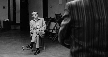 Movie still from “Broadway Danny Rose” (1984), directed by Woody Allen – A black and white photo of a man sitting on a chair; Medium shot, Over the shoulder angle