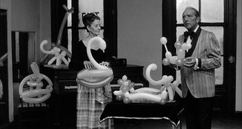 Movie still from “Broadway Danny Rose” (1984), directed by Woody Allen – A black and white photo of a woman holding balloons; Wide shot, Low angle