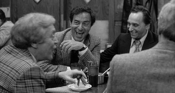 Movie still from “Broadway Danny Rose” (1984), directed by Woody Allen – A group of men sitting at a table laughing; Medium shot, Over the shoulder angle