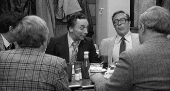 Movie still from “Broadway Danny Rose” (1984), directed by Woody Allen – A group of men sitting at a table with drinks; Medium shot, Over the shoulder angle