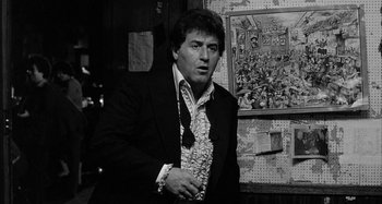 Movie still from “Broadway Danny Rose” (1984), directed by Woody Allen – Black and white photograph of a man wearing a suit and tie; Medium shot, Low angle