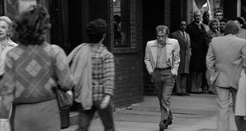 Movie still from “Broadway Danny Rose” (1984), directed by Woody Allen – A black and white photo of a man walking down the street; Wide shot, Over the shoulder angle