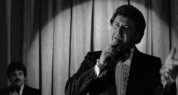 Movie still from “Broadway Danny Rose” (1984), directed by Woody Allen – A black and white photo of a man singing into a microphone; Close Up shot, Low angle