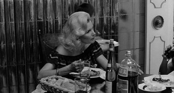 Movie still from “Broadway Danny Rose” (1984), directed by Woody Allen – A black and white photo of a woman sitting at a dinner table; Medium shot, Over the shoulder angle