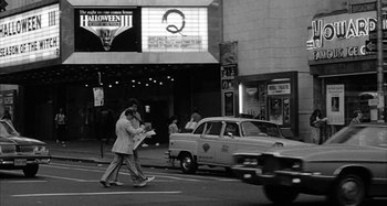 Movie still from “Broadway Danny Rose” (1984), directed by Woody Allen – A black and white photo of a man crossing the street; Wide shot, High angle