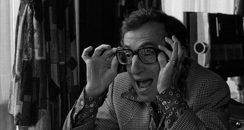 Movie still from “Broadway Danny Rose” (1984), directed by Woody Allen – A man in a jacket and glasses is holding his hands up to his face; Close Up shot, Over the shoulder angle
